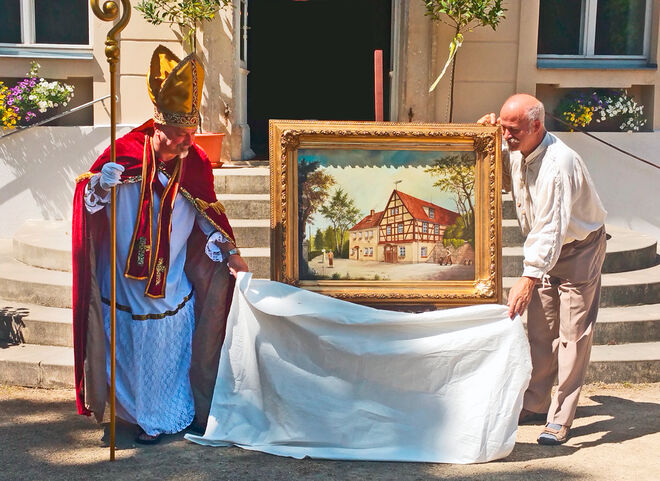 Roland Schwenke (re.) enthüllt gemeinsam mit dem anwesenden „Bischof Benno“ das Gemälde Lauterbacher Kellerschenke.