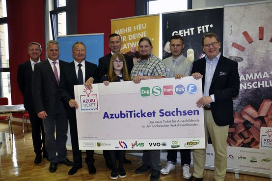 Martin Duhlig (Mitte hinten) übergibt gemeinsam mit den Geschäftsführern der Verkehrsverbünde symbolisch das AzubiTicket an Auszubildende.